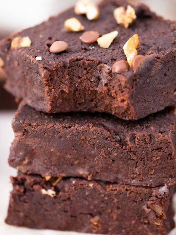 Chickpea brownies stacked with a bite taken out from the top brownie.