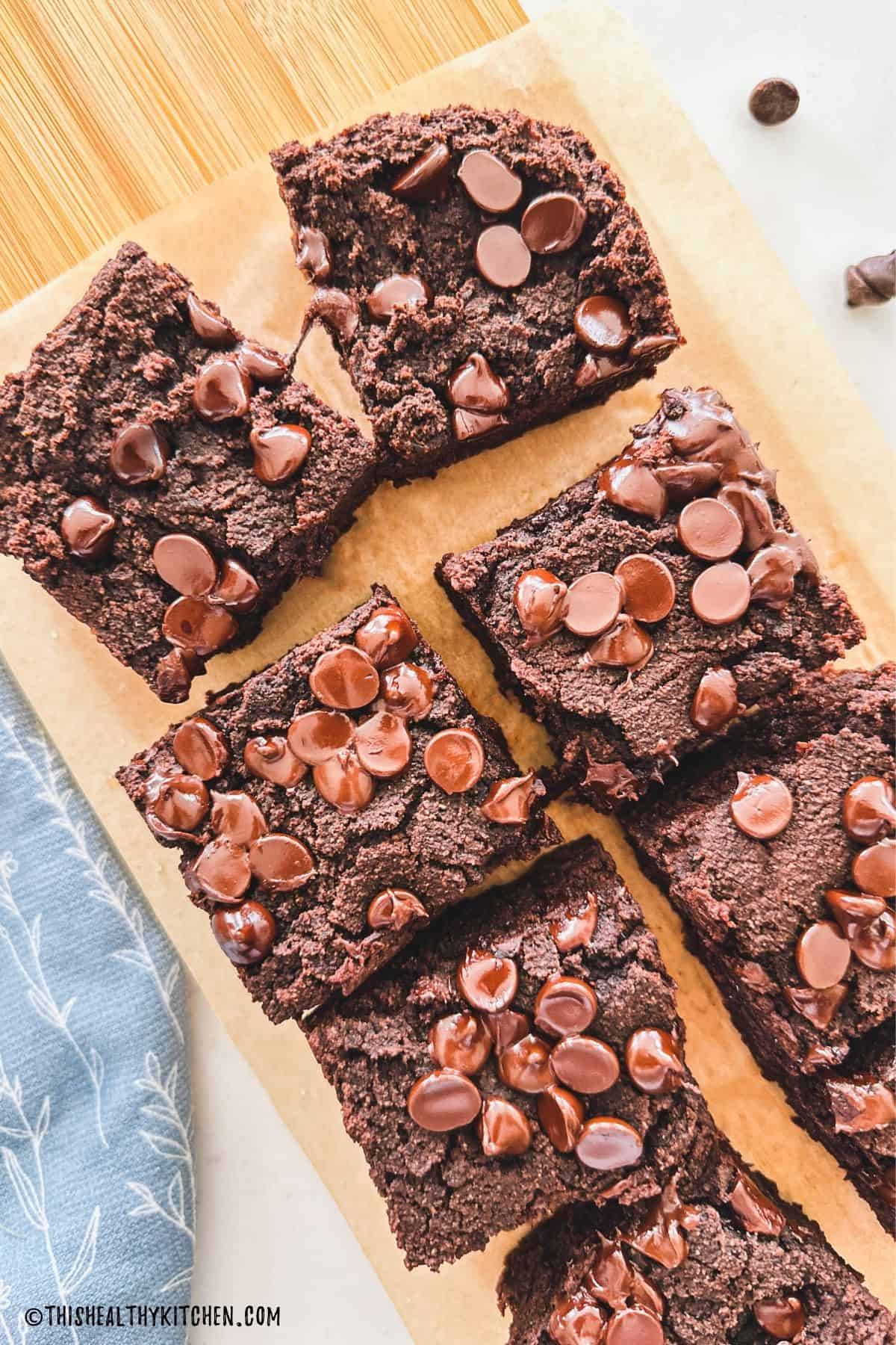 Chocolate cake squares with chocolate chips on cutting board.
