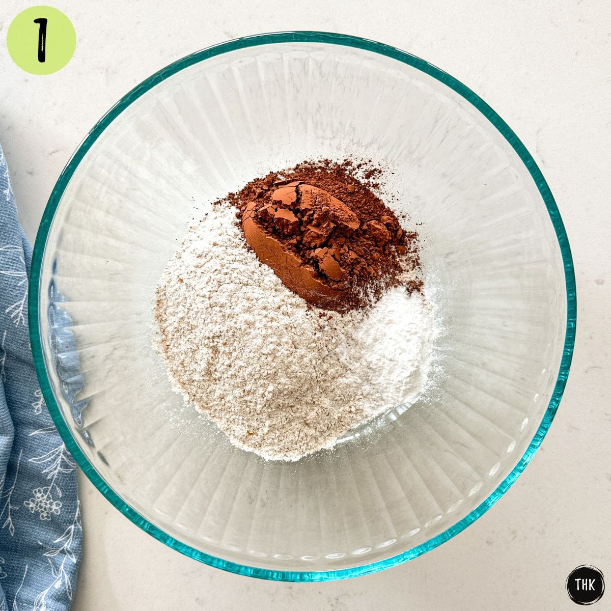 Large glass bowl with flour, cocoa powder and baking powder inside.
