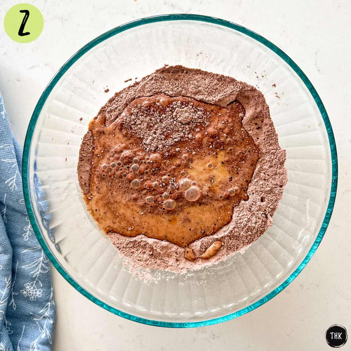 Glass mixing bowl with unmixed chocolate waffle batter inside.
