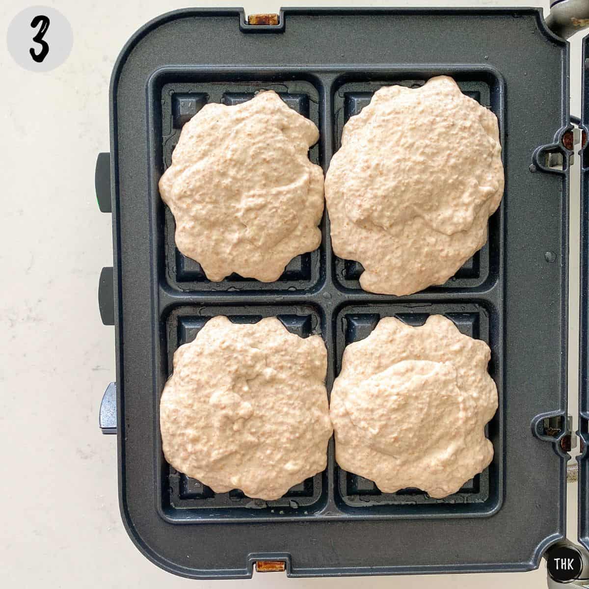 Raw waffle batter on waffle iron.