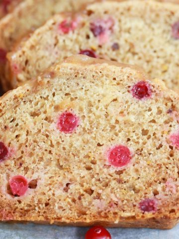 Slices of cranberry orange bread with orange half beside them.