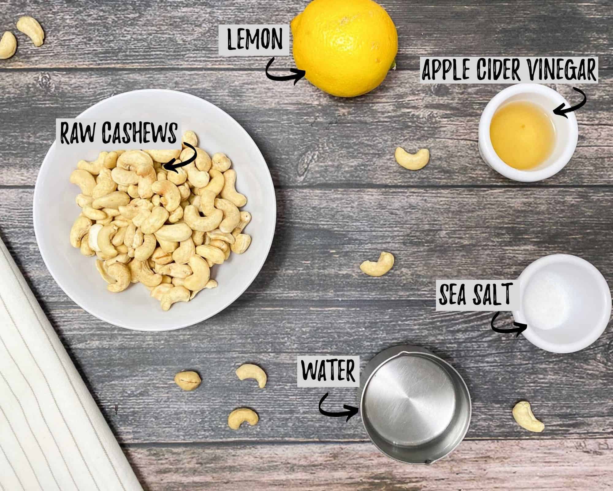 bowl of cashews, lemon, salt, vinegar and water on grey deck