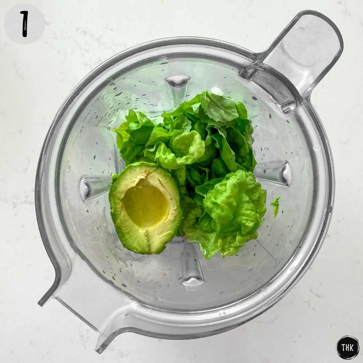 Blender with basil, avocado, vinegar and chives inside.