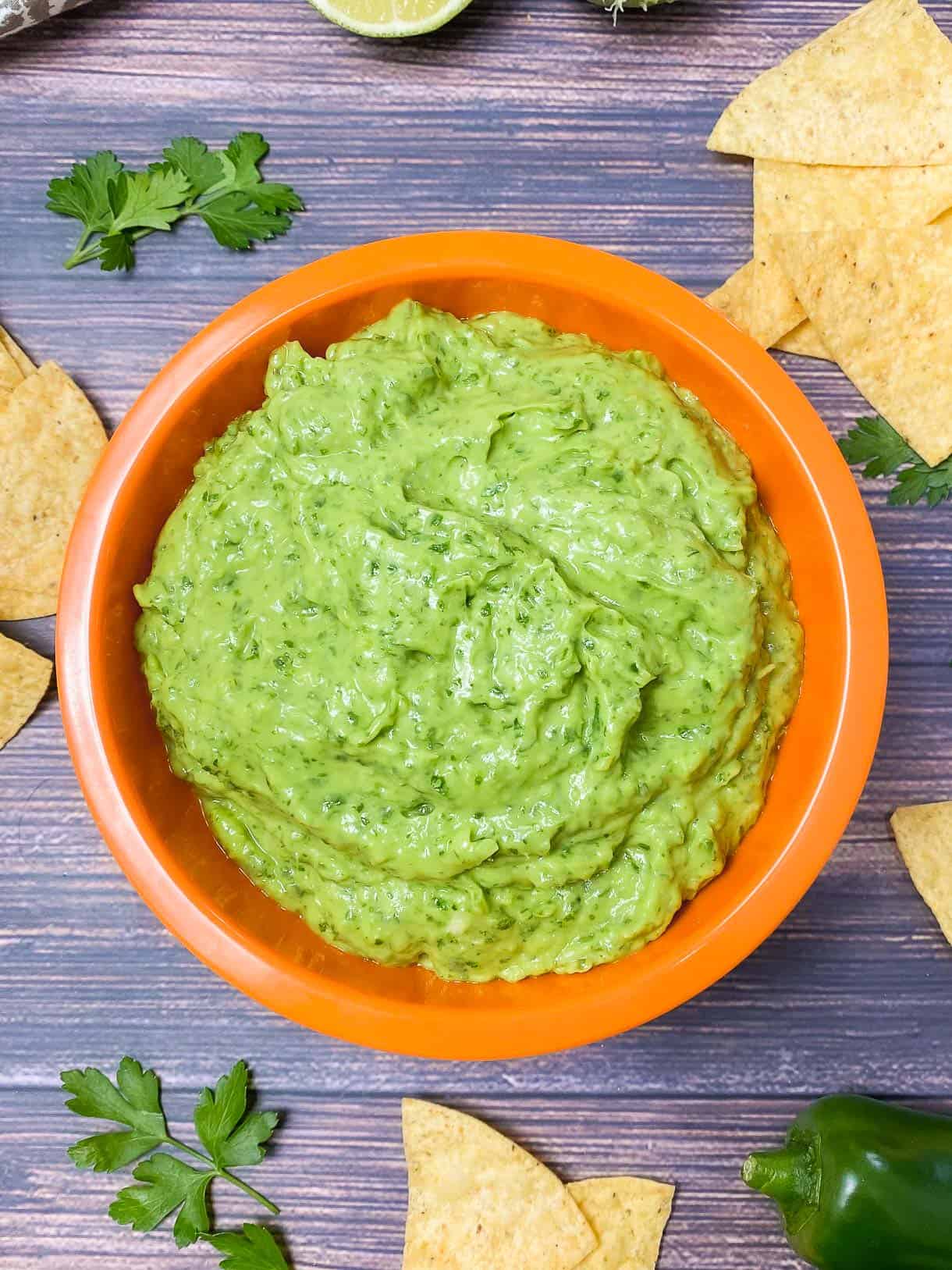 green dip in orange bowl with chips in the background