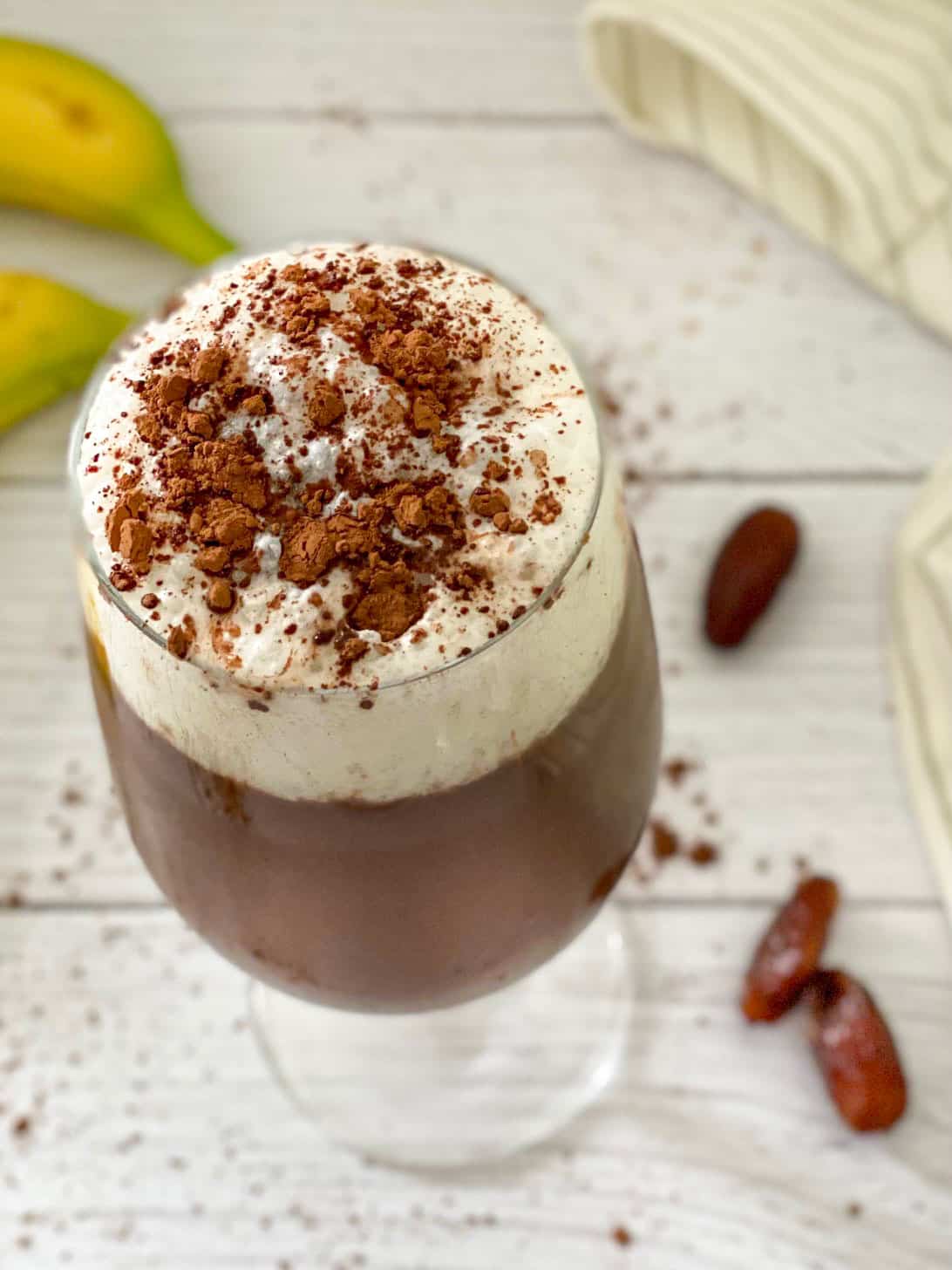 Overhead view of glass with iced mocha with dates and bananas around it.