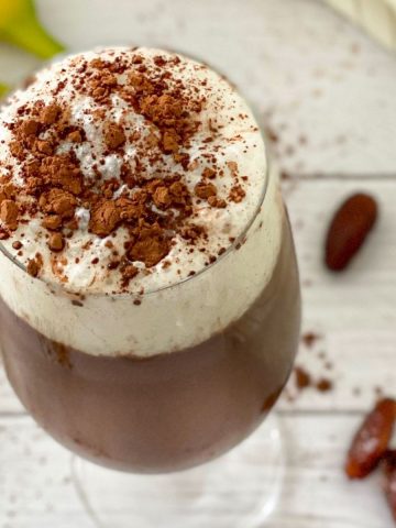 Overhead view of glass with iced mocha with dates and bananas around it.
