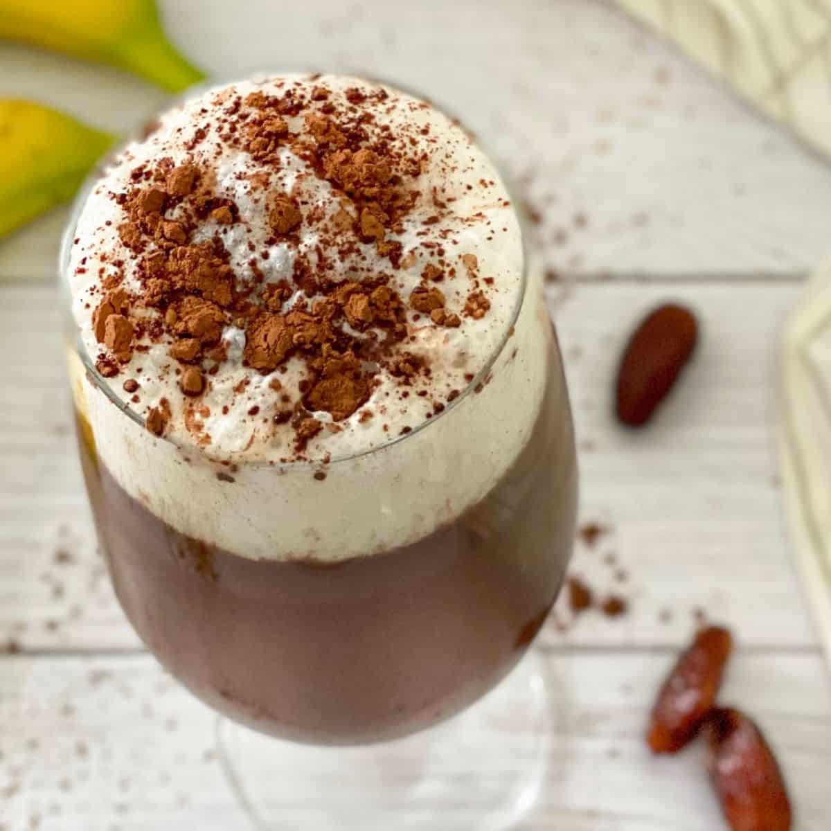 Overhead view of glass with iced mocha with dates and bananas around it.
