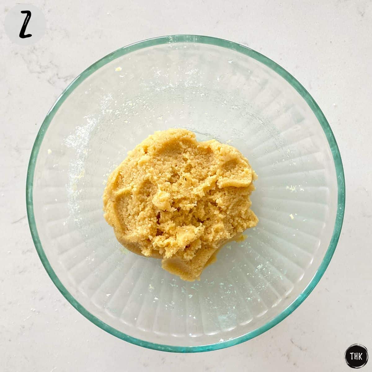 Glass mixing bowl with ball of dough inside.