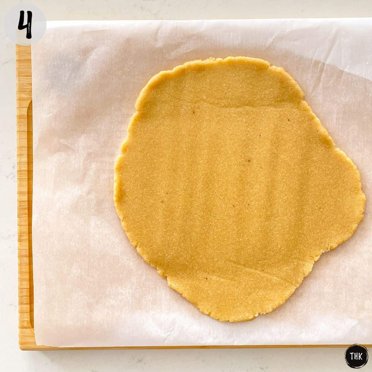 Stretched out dough on top of parchment paper.