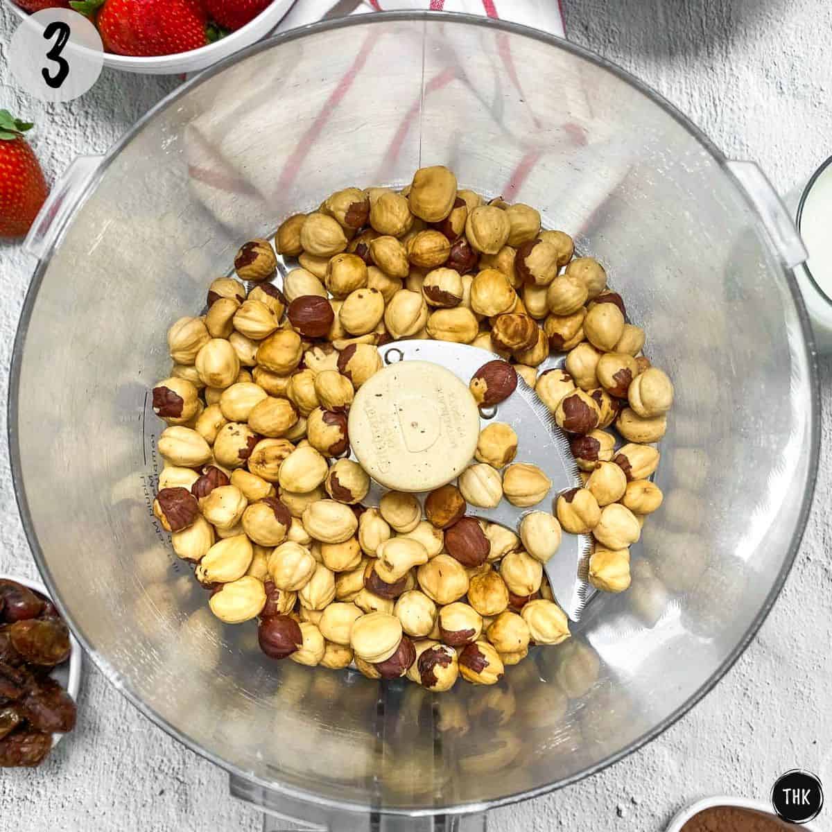 Roasted hazelnuts inside food processor.