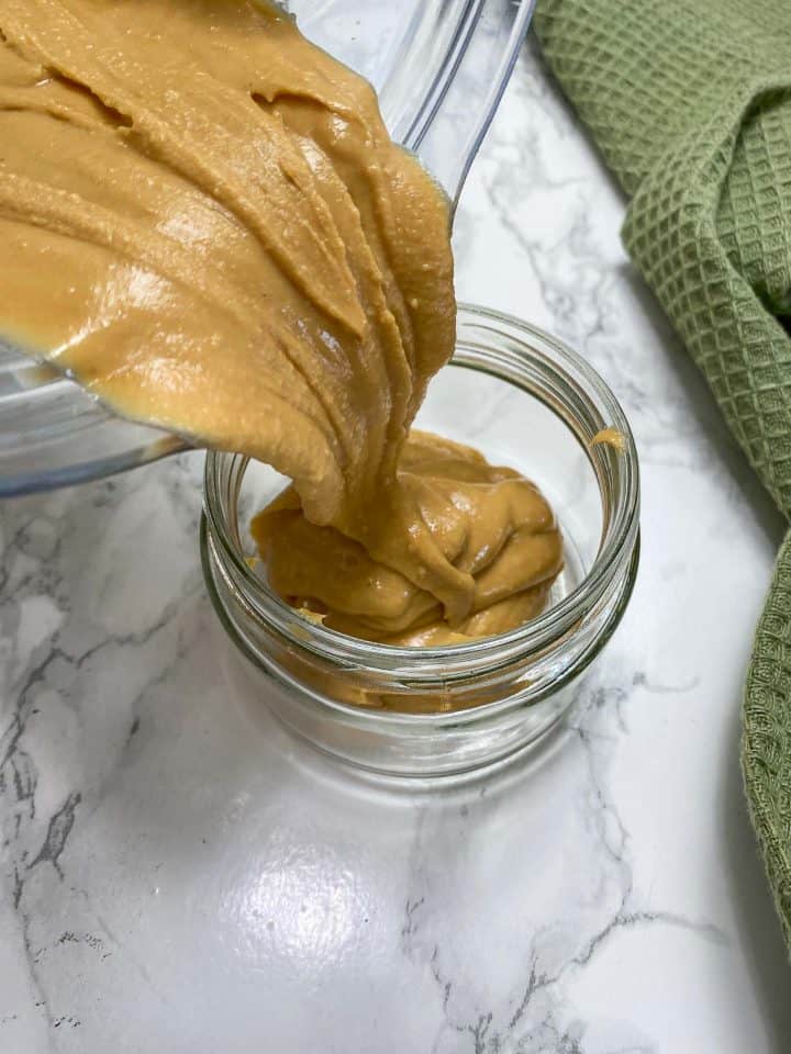 pouring peanut butter from blender into jar