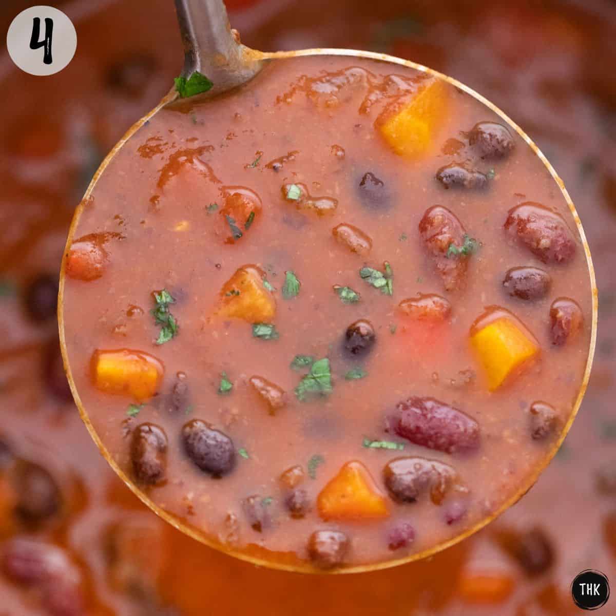 Ladle filled with bean and vegetable soup held above pot.
