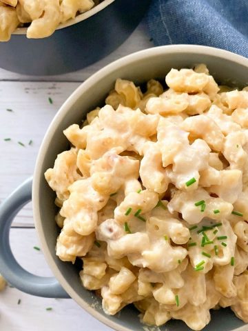 vegan mac and cheese in blue bowl with chives garnished on top.