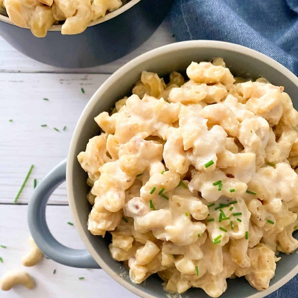 vegan mac and cheese in blue bowl with chives garnished on top.