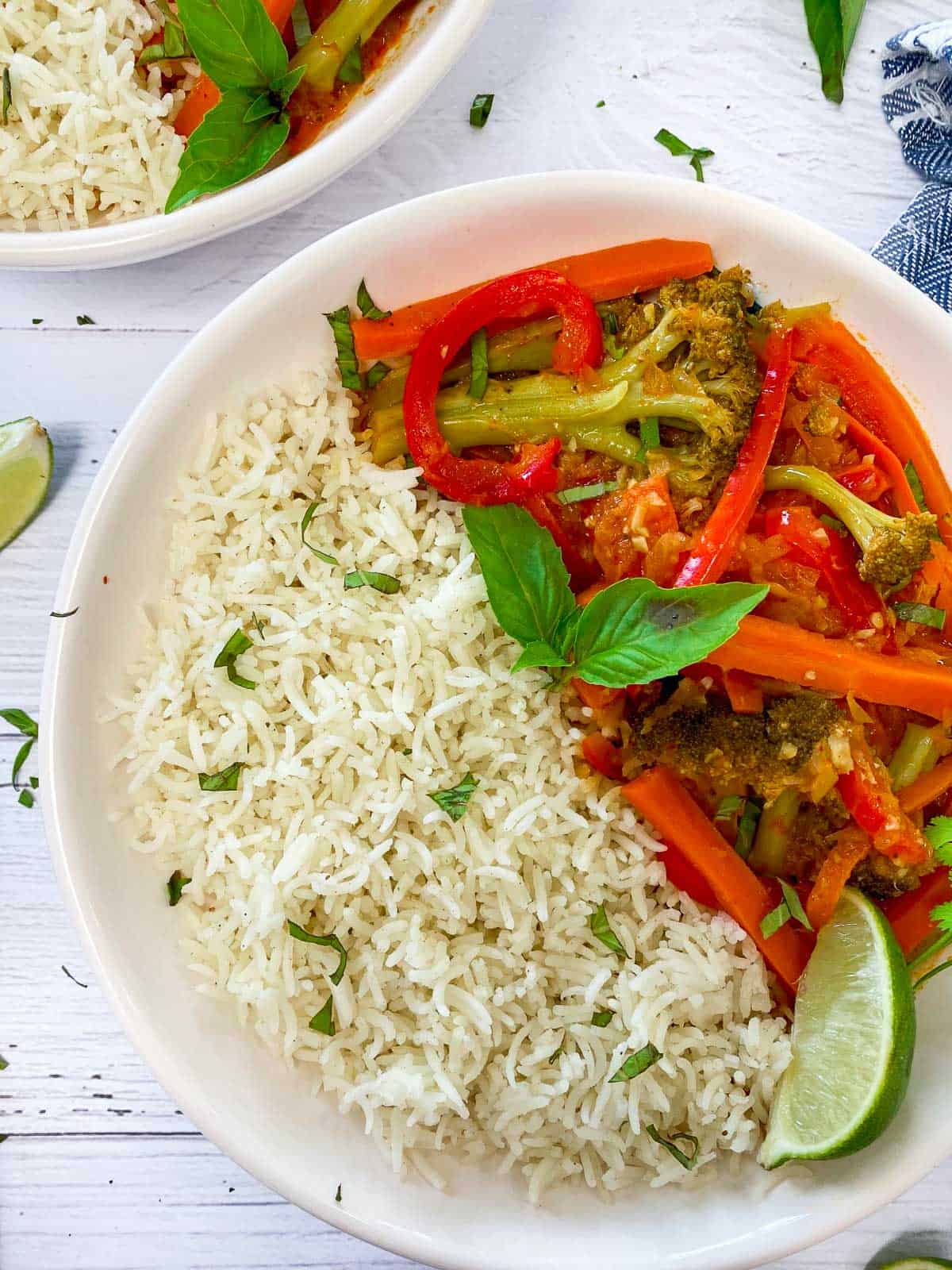 close up image of white bowl half filled with rice and the other half filled with veggies covered in a red curry sauce