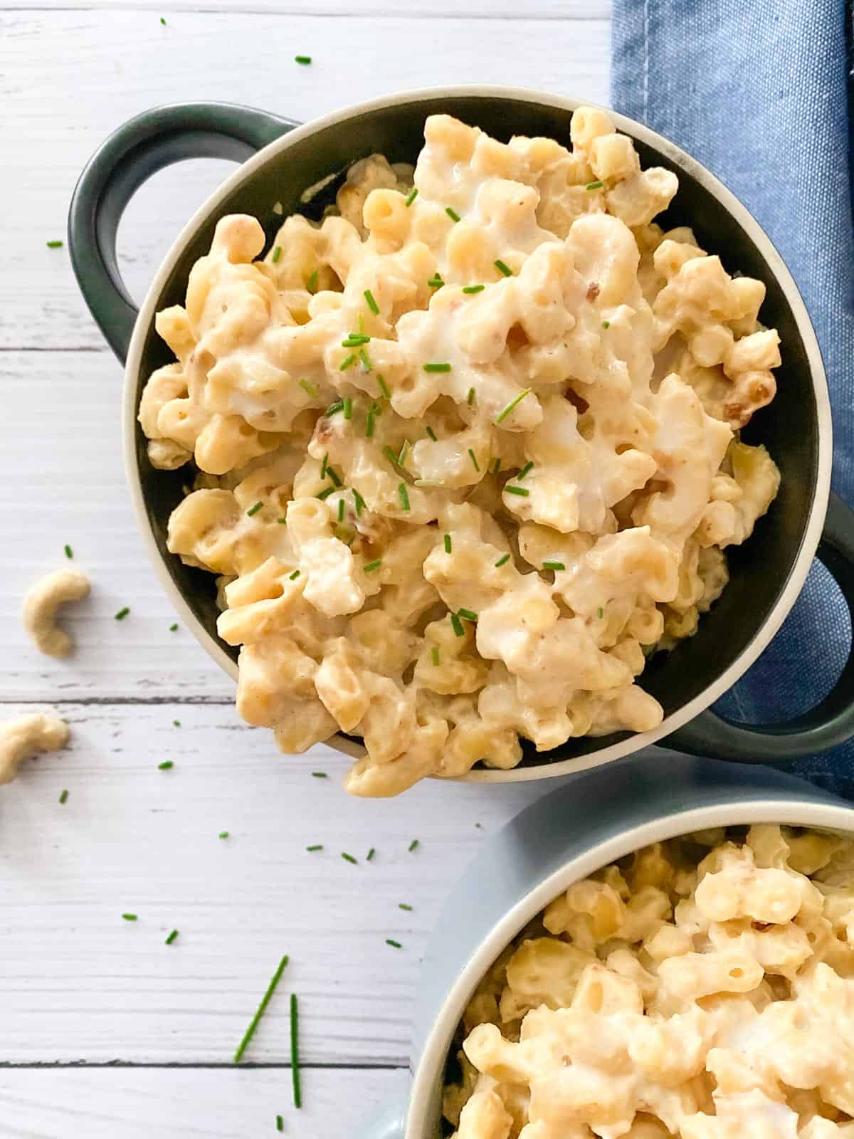 Black bowl filled with vegan mac and cheese and chives garnished on top.