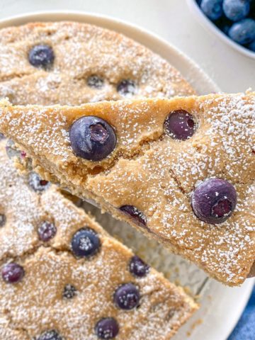 Triangle lifting slice of blueberry cake from plate.