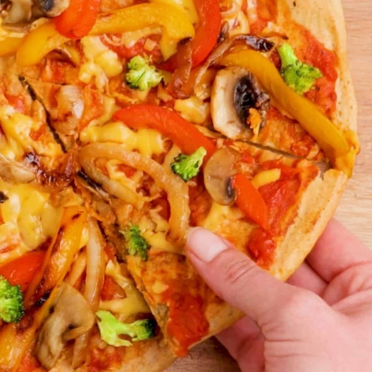 hand lifting slice of pizza from cutting board.