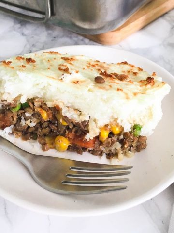 slice of lentil shepherd's pie in plate with fork.