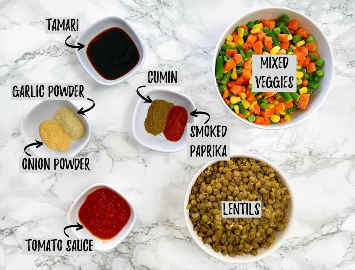 Bowls of ingredients needed to make lentil shepherd's pie on marble counter.