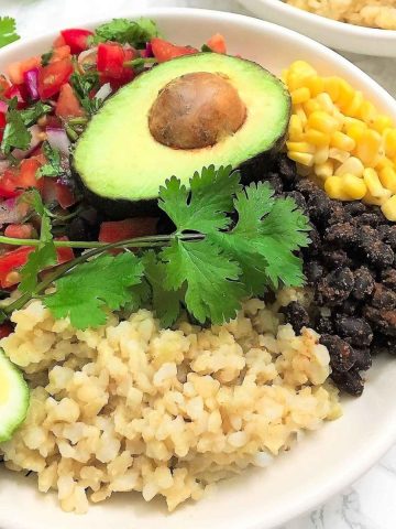 Bowl of rice, black beans, corn, tomato salad and avocado.