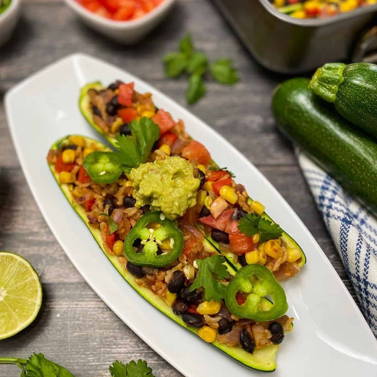 Two zucchini halves stuffed with beans, rice, veggies and guacamole.