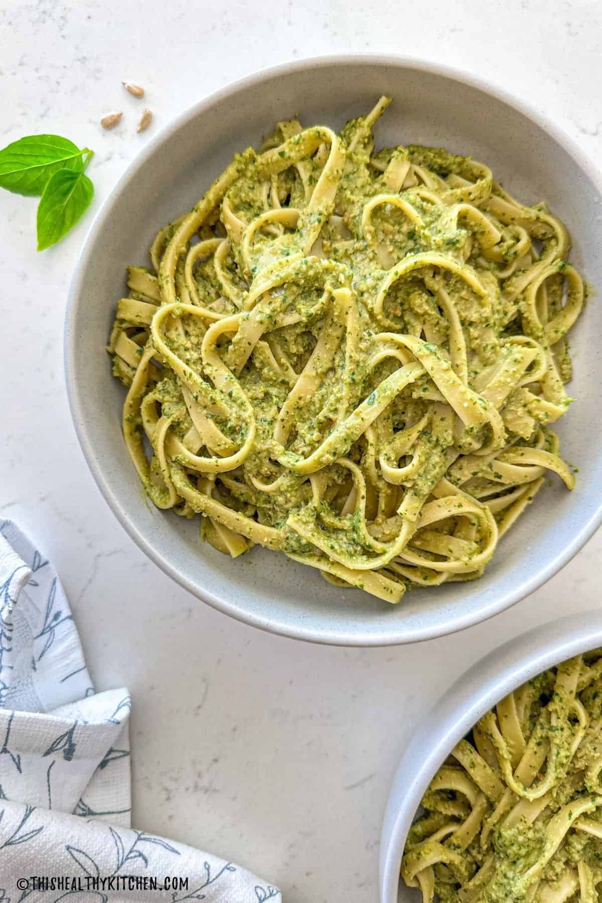 Two bowls of fettuccini pasta covered in miso pesto sauce.