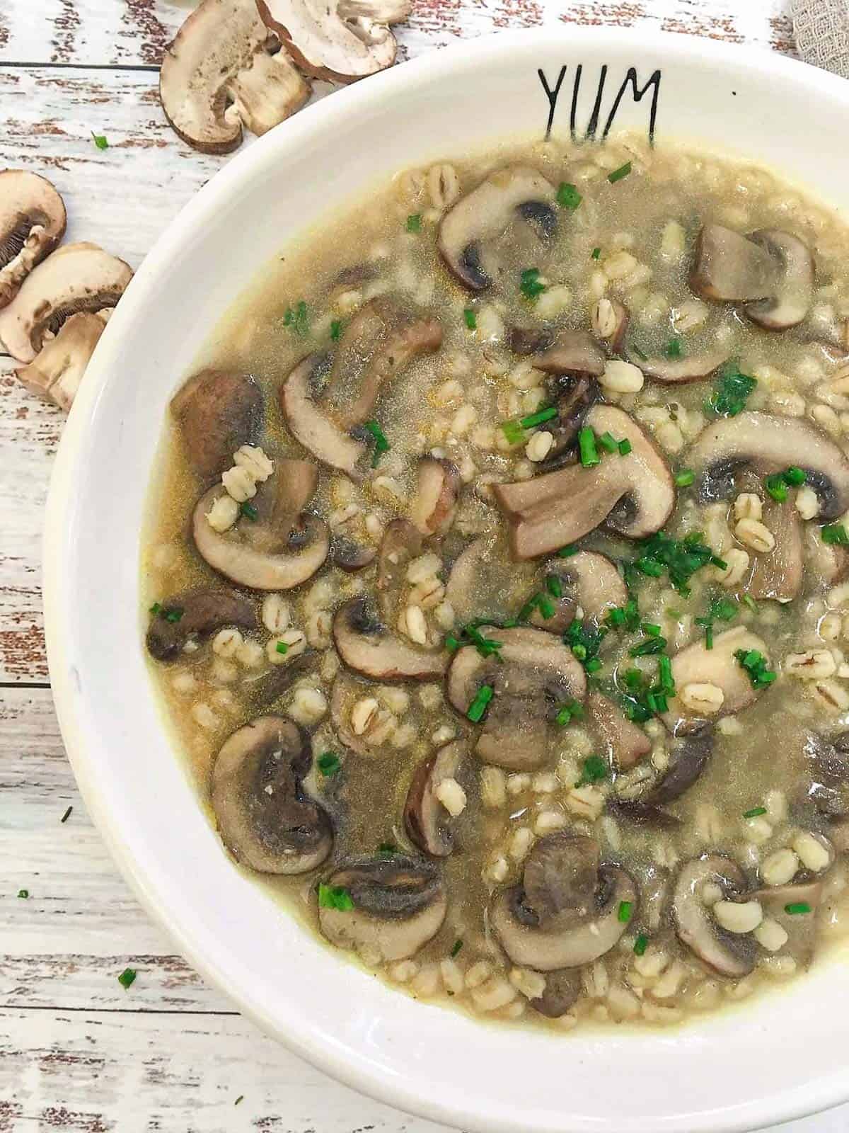 White bowl with "yum" written on the side and mushroom soup inside.