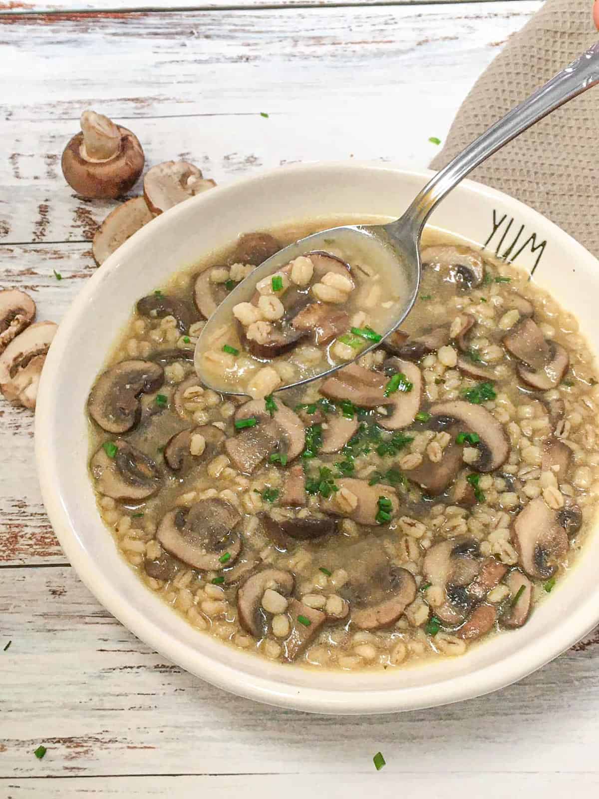 Spoonful of mushroom barley soup being lifted from bowl.