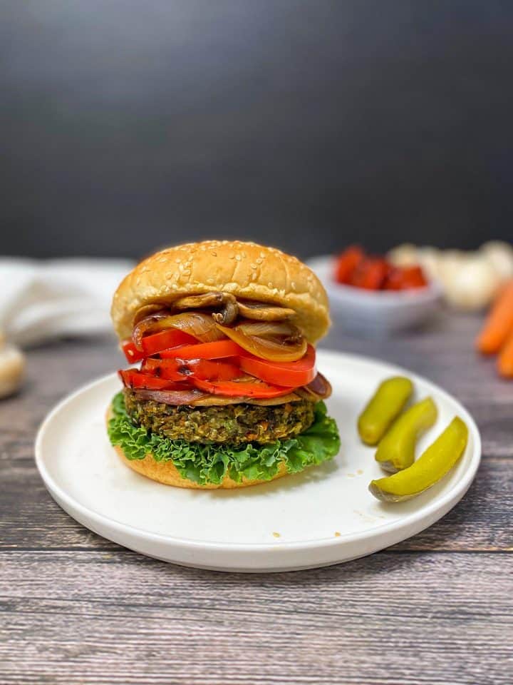 mushroom risotto burger on white plate with pickles on the side