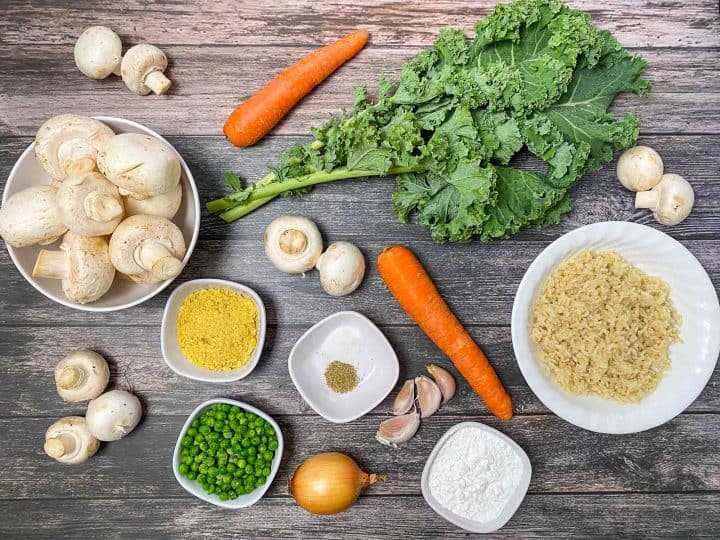 kale, carrot, mushrooms, peas, garlic, onion and bowl of rice on grey deck