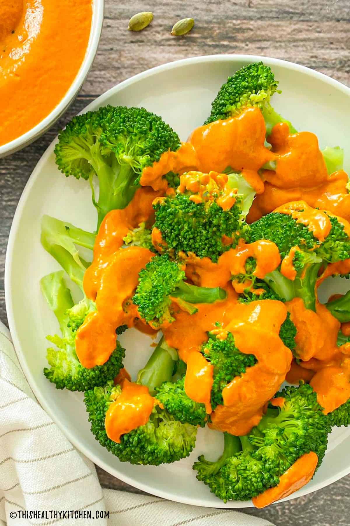 Plate of broccoli with orange cheese sauce drizzled on top.