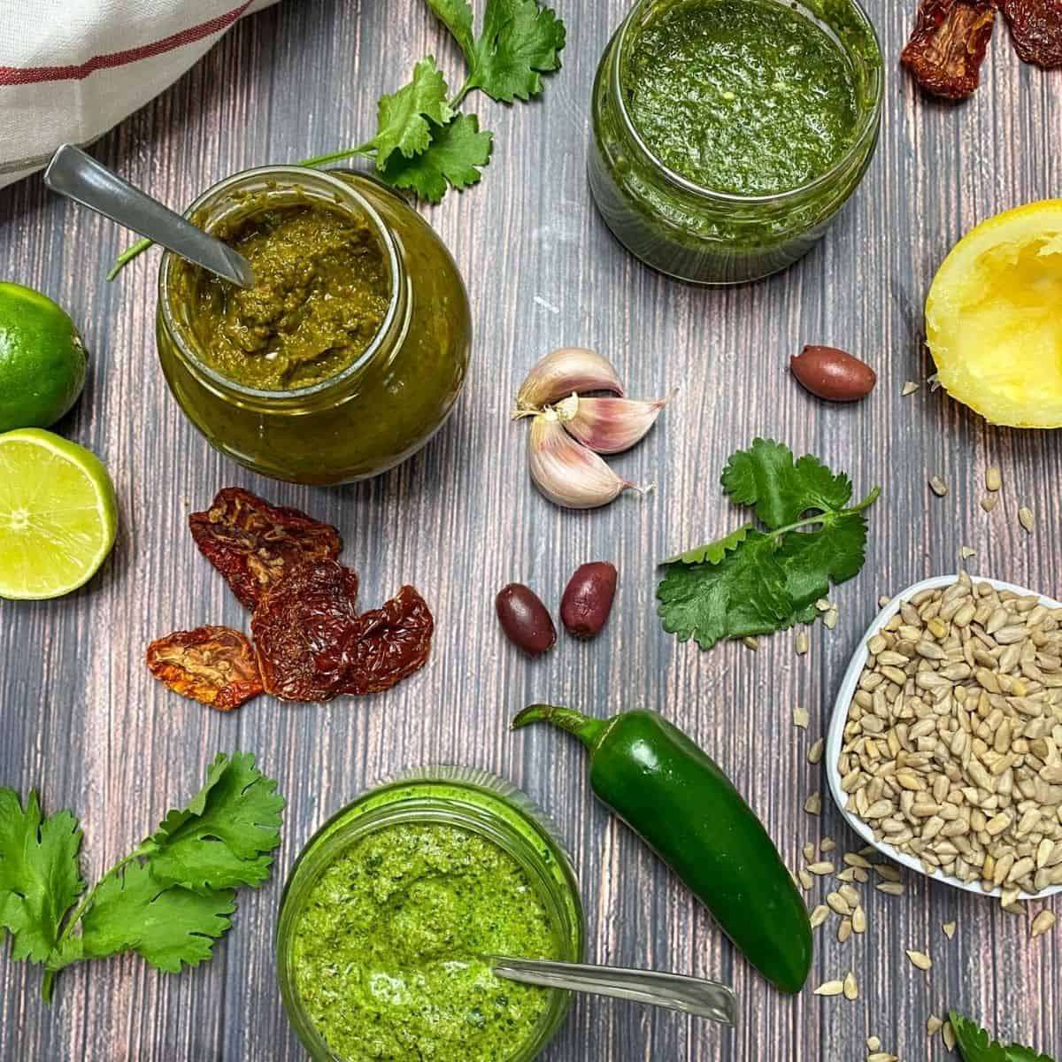 Three glass jars filled with pesto with lids off