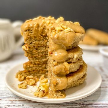Peanut butter pancakes in a stack on plate with triangular wedge cut out.