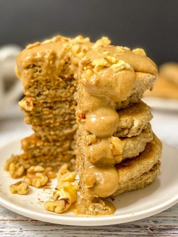 Peanut butter pancakes in a stack on plate with triangular wedge cut out.