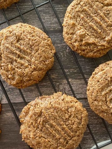 Cooling rack with pecan cookies on top and pecans on the side.