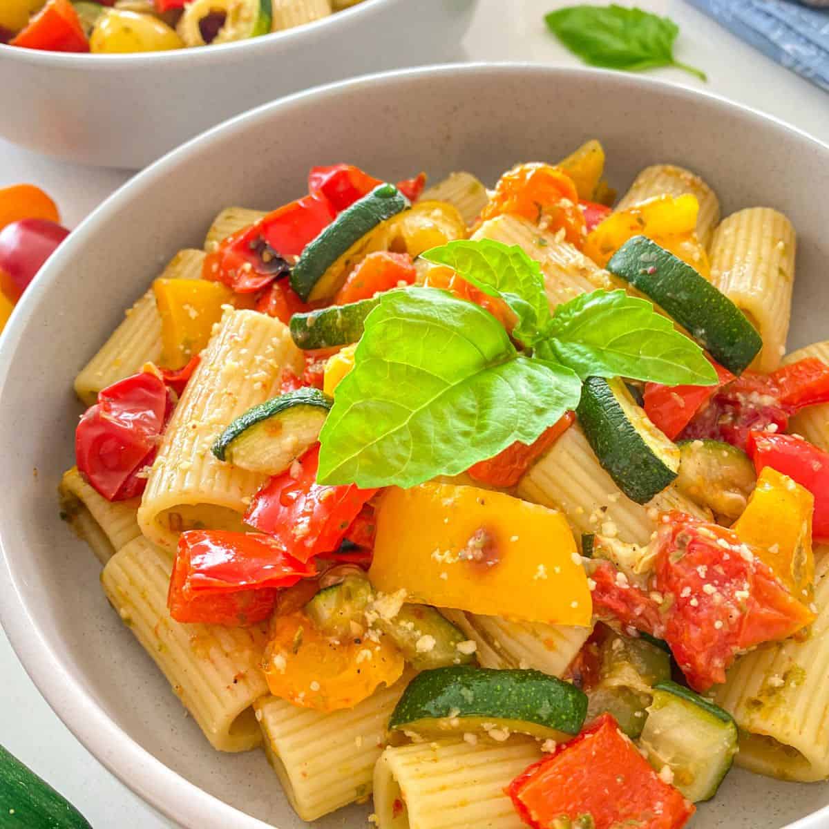Side view of plates with pesto pasta and veggies inside.