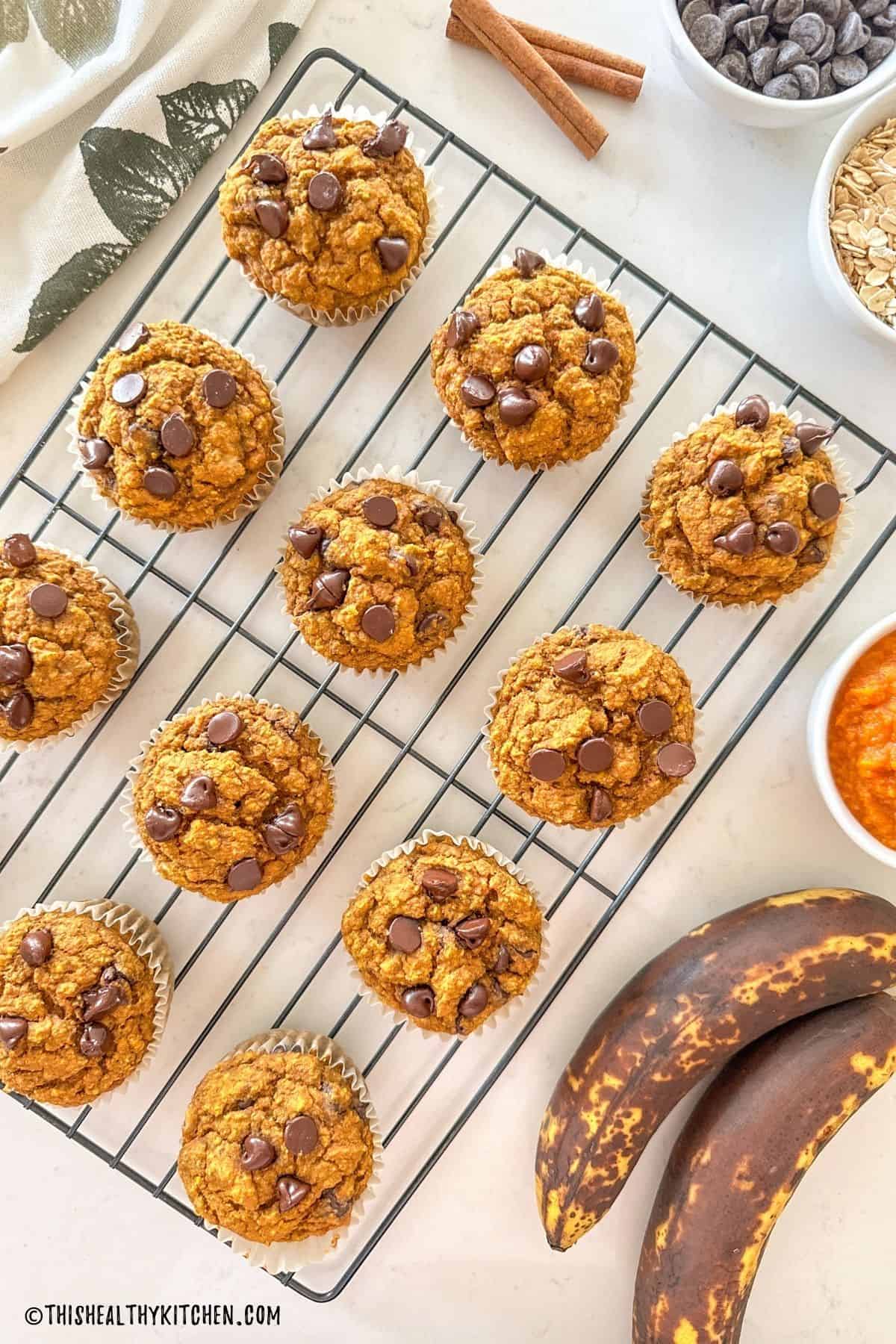 Pumpkin banana muffins with chocolate chips on wire rack.