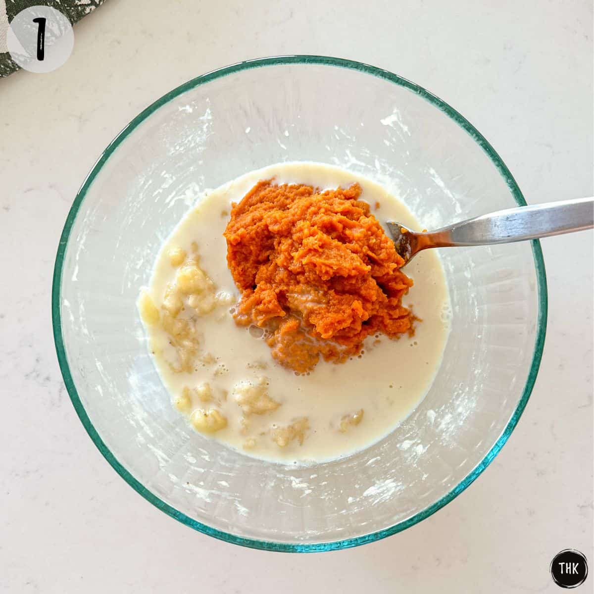 Mashed banana, pumpkin puree, and milk in a large mixing bowl.