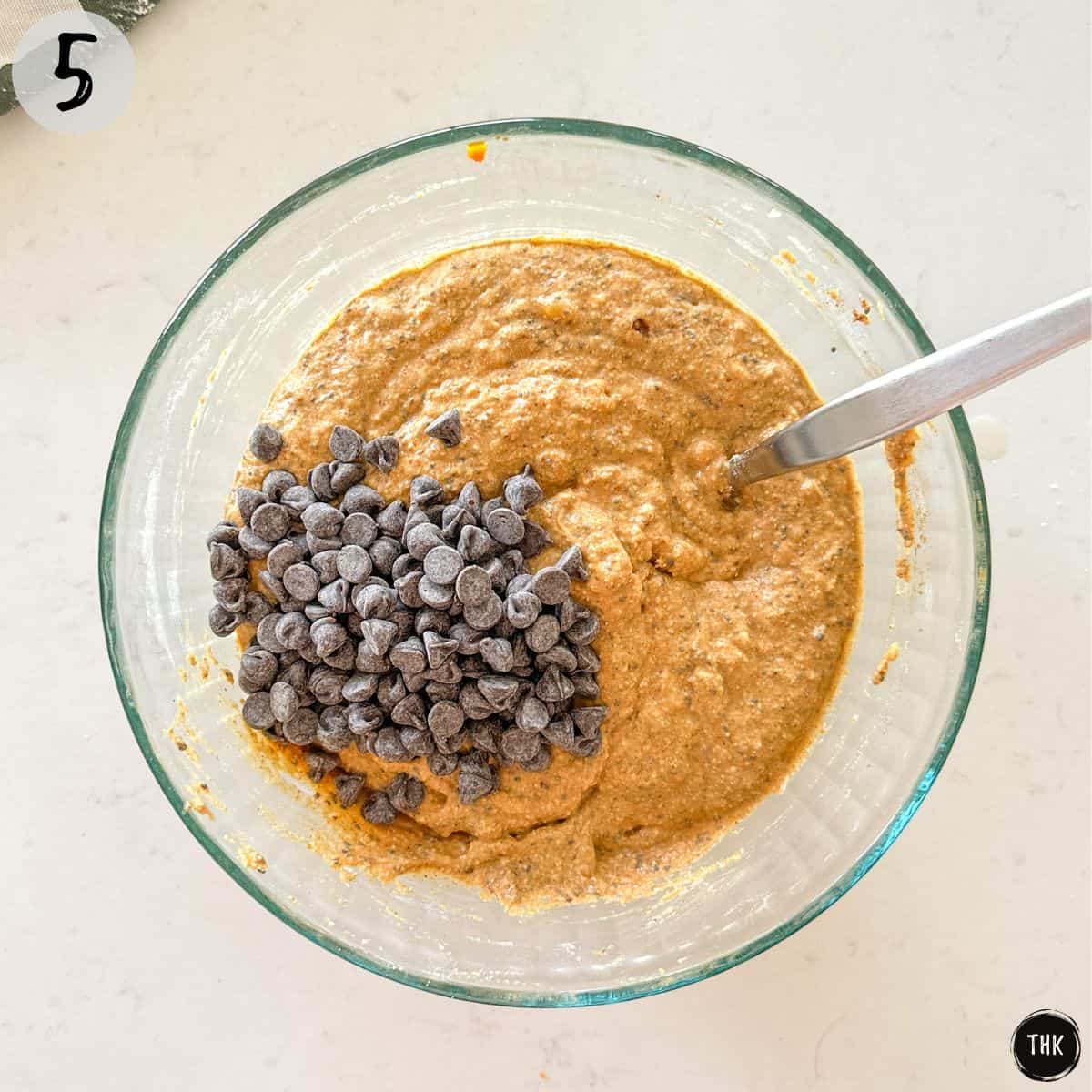 Muffin batter in mixing bowl with chocolate chips on top.