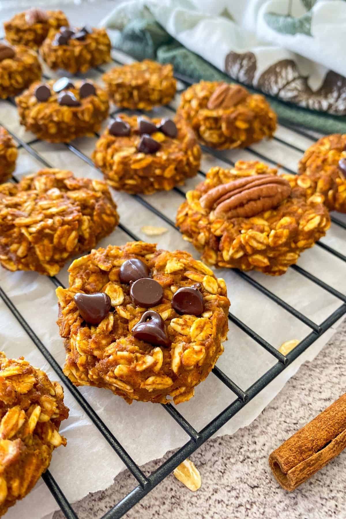 Side view of oatmeal cookies on cooling rack with chocolate chips and pecan halves on top.