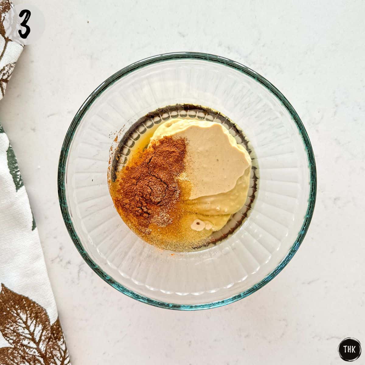 Tahini, vinegar, maple syrup, and spices inside small mixing bowl.