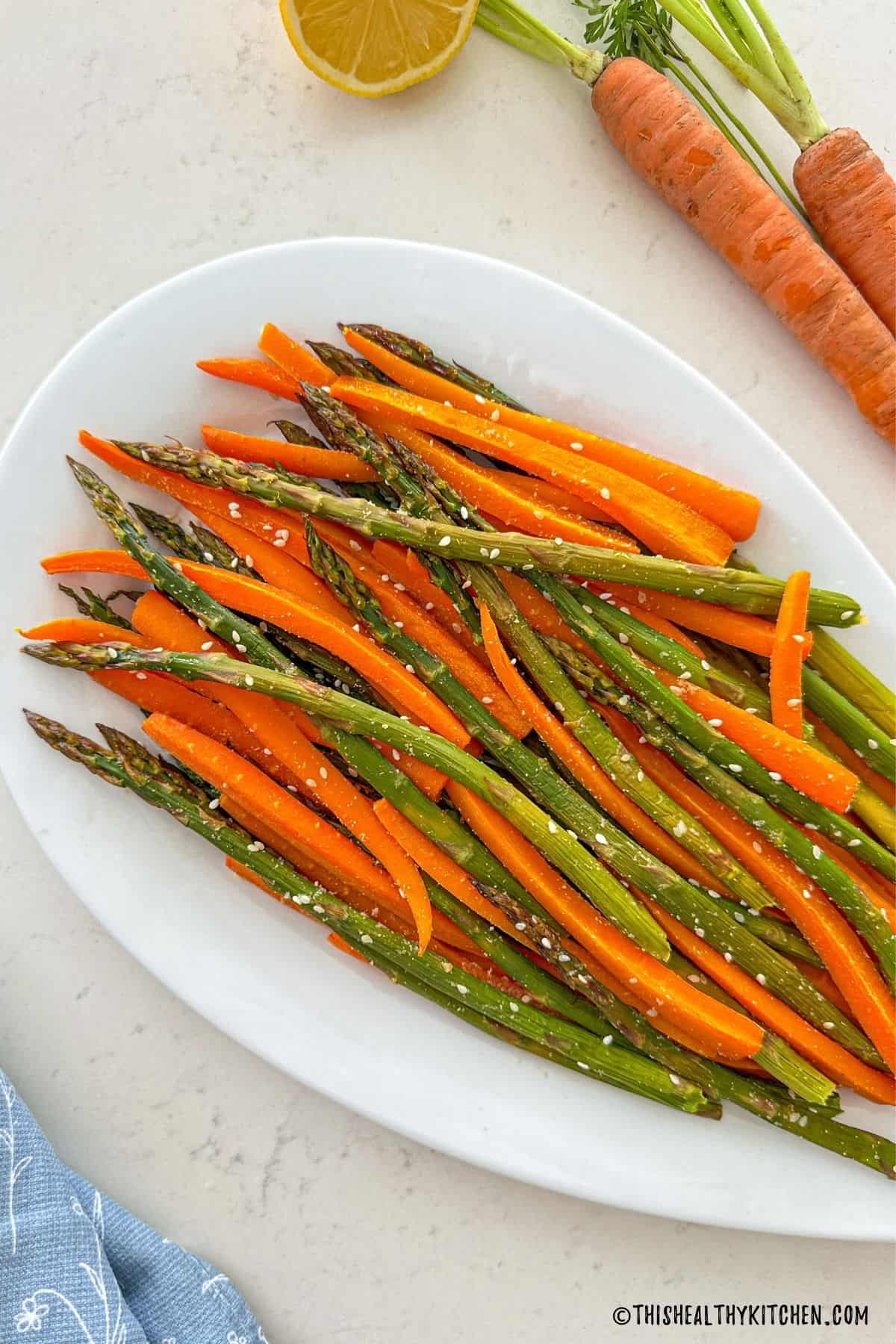 Roasted asparagus and carrots on white serving platter.