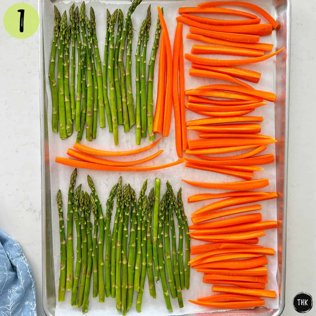 Baking tray with asparagus and carrot spears in a single layer.