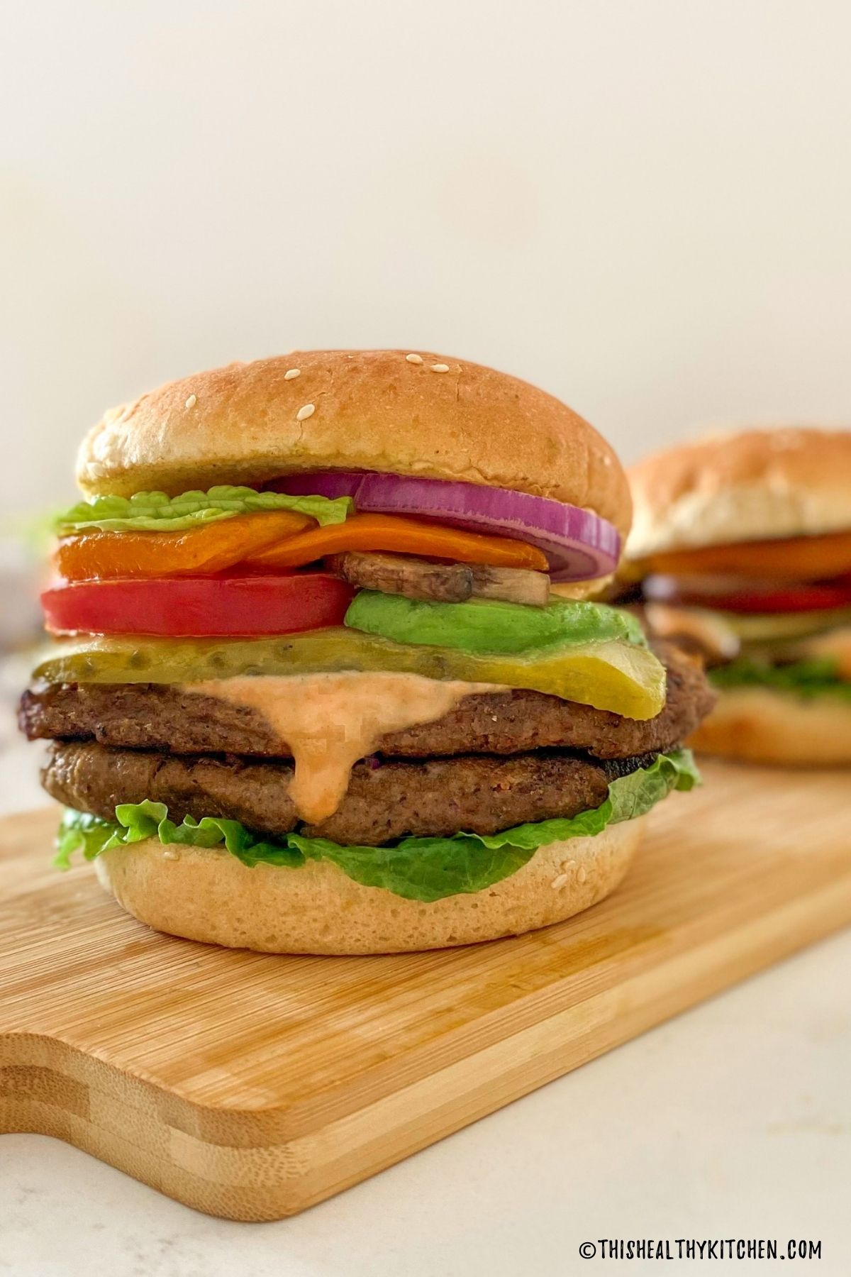 vegan burger in bun with tomato, lettuce, pickle, onion and spicy mayo.