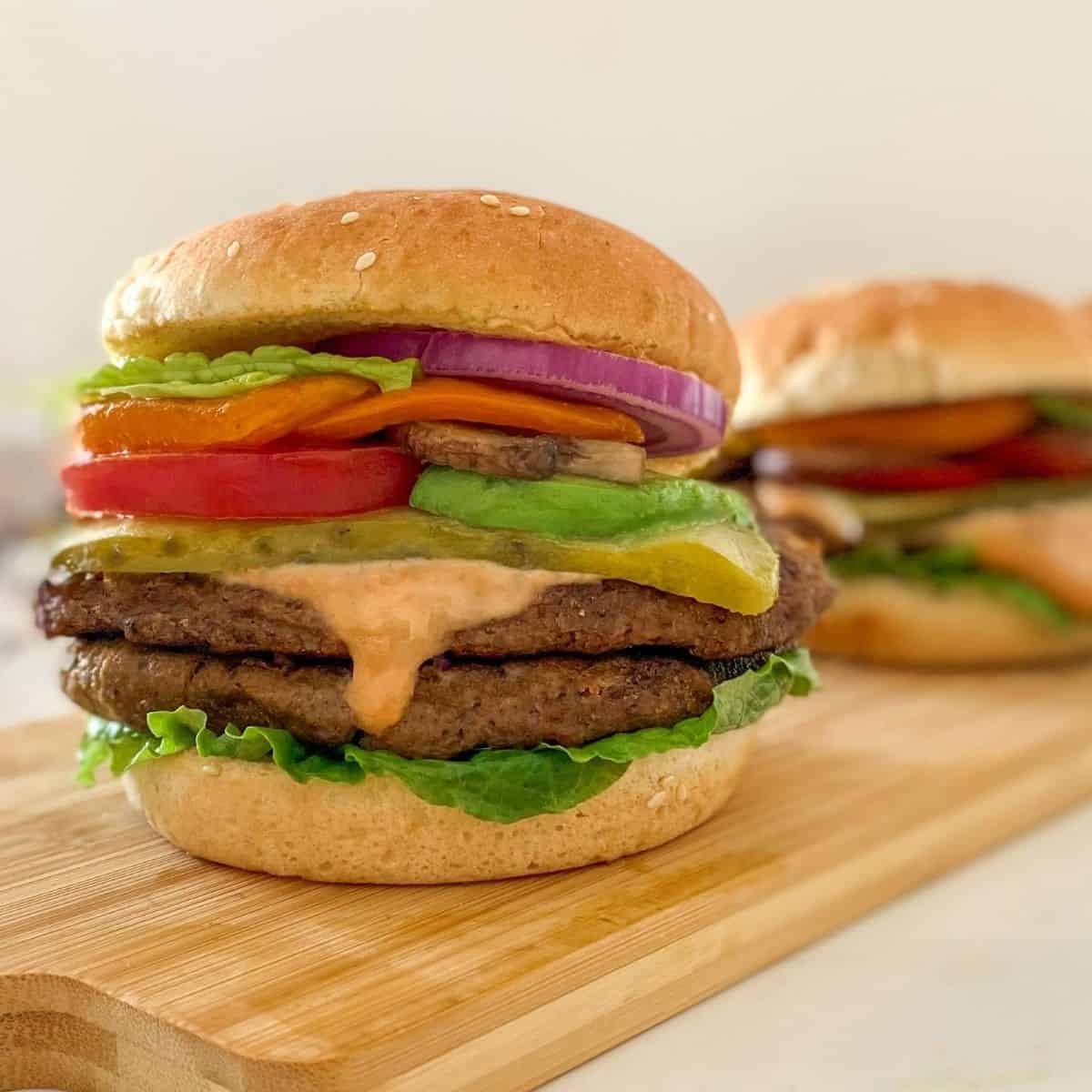 vegan burger in bun with tomato, lettuce, pickle, onion and spicy mayo.