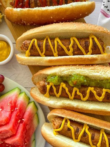 Vegan hot dogs in buns with mustard and relish on top.