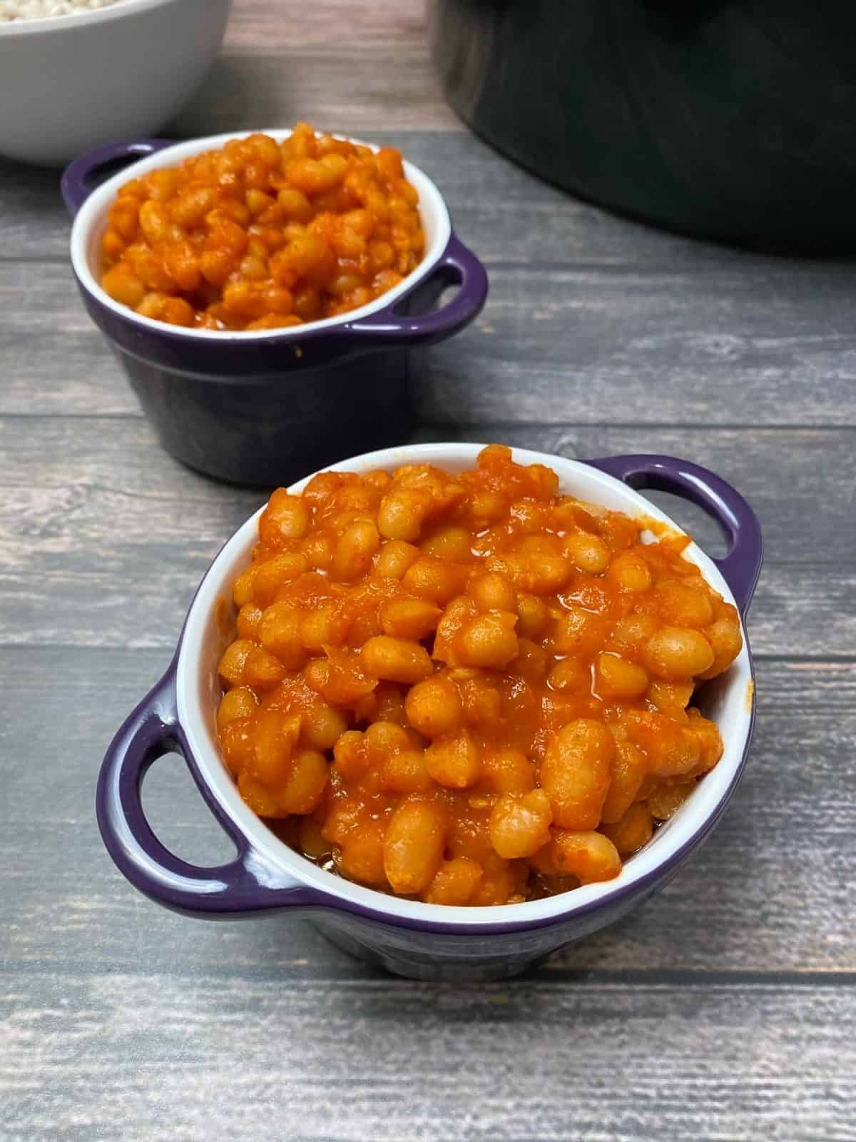 two purple bowls filled with beans in bbq sauce
