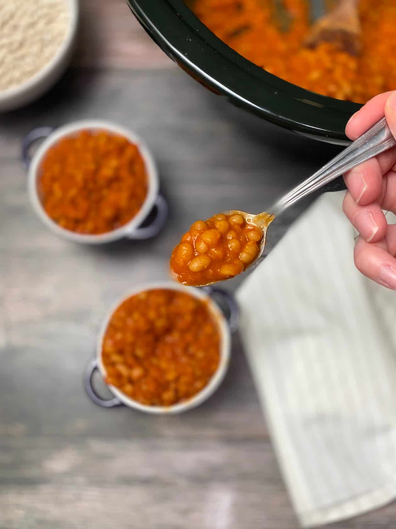 spoon picking up bite of baked beans from purple bowl
